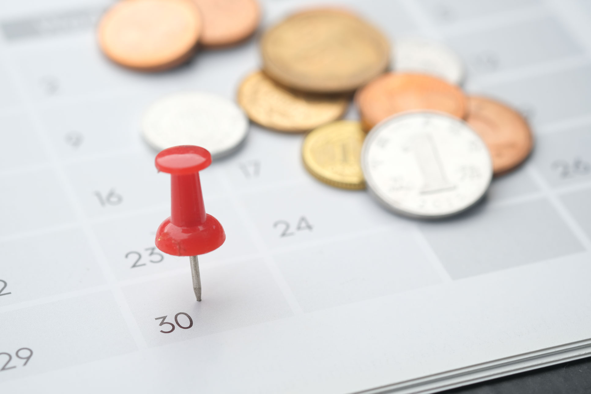 Échéance de paiement marquée sur un calendrier avec des pièces de monnaie en arrière-plan, symbolisant les règlements clients