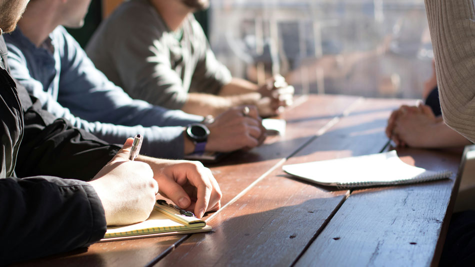 Ordinateur portable à moitié fermé sur un bureau en bois, évoquant l'absence de travail ou une pause liée à un congé ou un arrêt de travail.